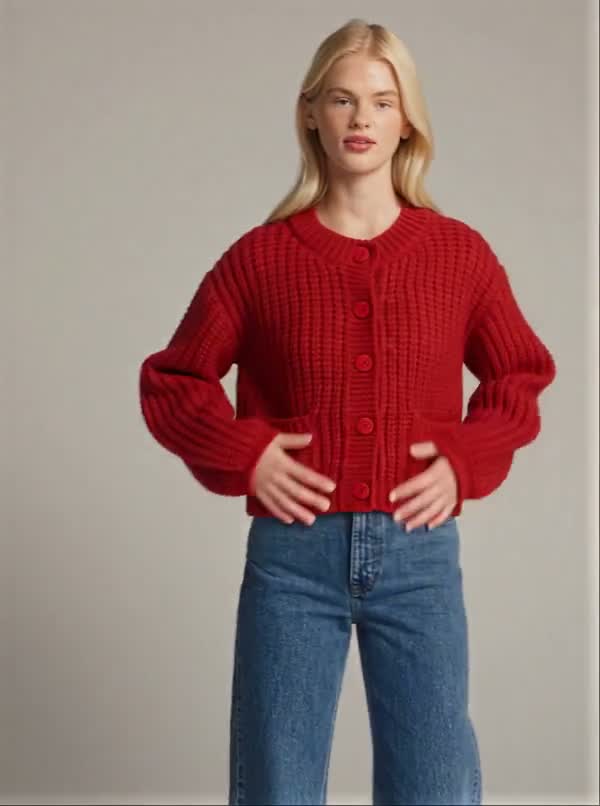 A model wearing a red textured cardigan and denim